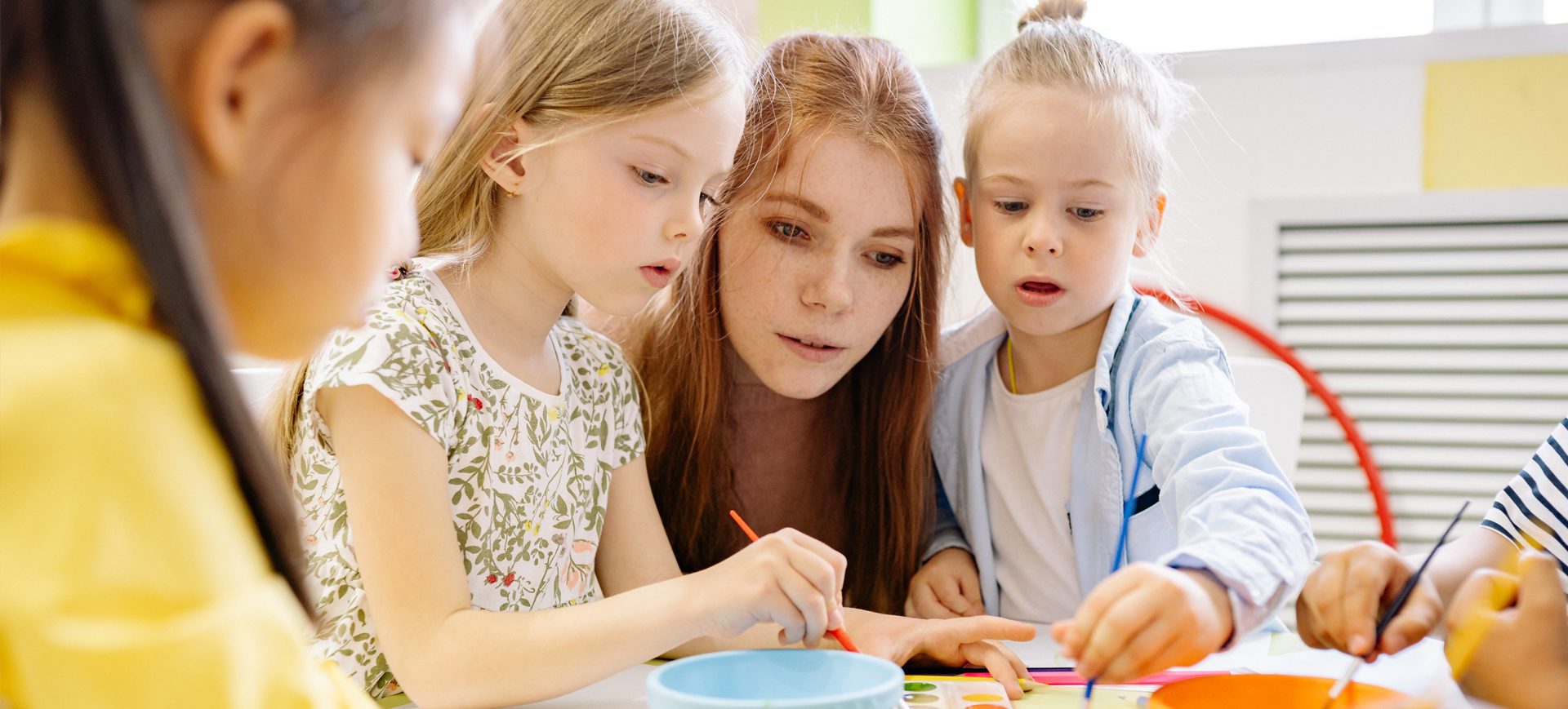 A woman and two young girls painting with paint.